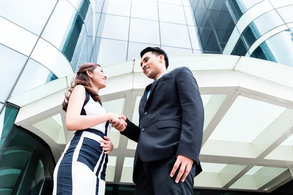 Asian businesspeople handshake in front of high rise building — Stock Photo, Image