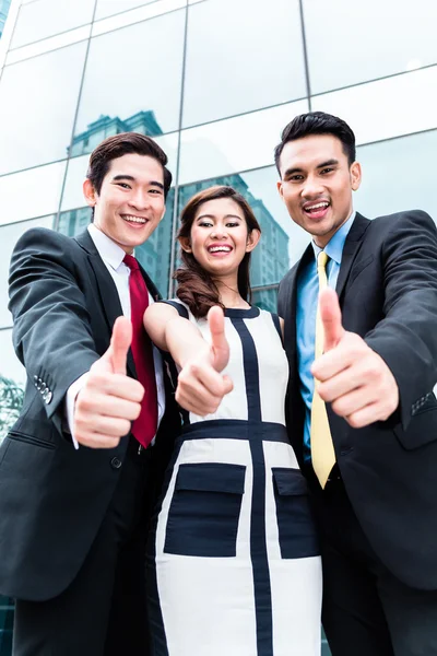 Asian businesspeople outside in front of skyscraper — Stock Photo, Image