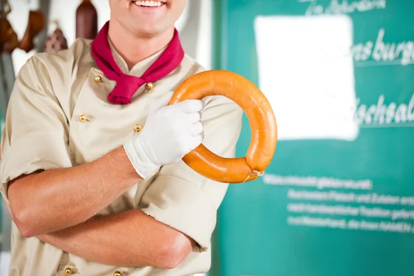 Butcher with fresh sausage at shop — Stock Photo, Image