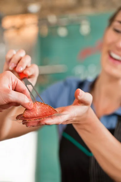 Carnicero hembra vendiendo carne fresca al cliente — Foto de Stock