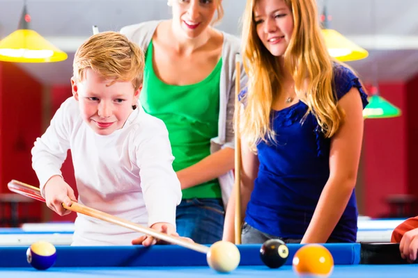 Boy playing pool billiard with family Stock Photo