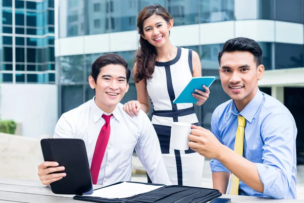 Asian businesspeople working outside with coffee — Stock Photo, Image
