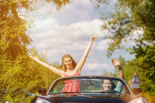 Jovem casal com carro cabriolet na primavera — Fotografia de Stock