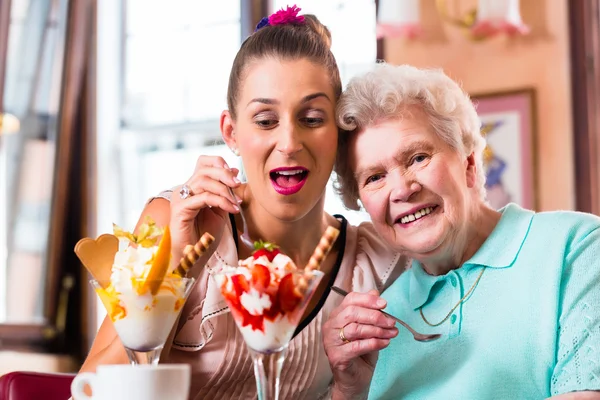 Vrouw en kleindochter eten van ijs in café — Stockfoto