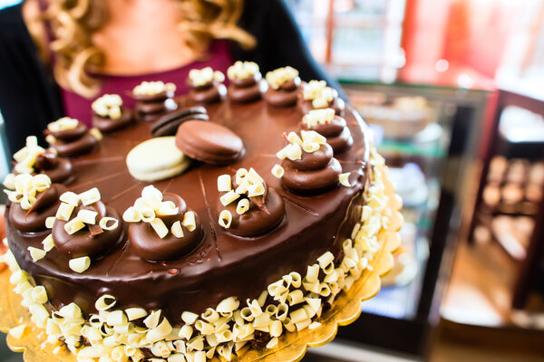 Female baker presenting cake in confectionery