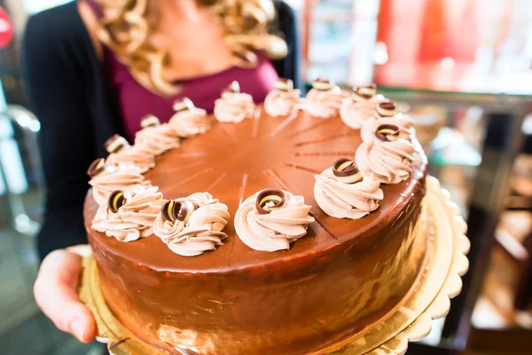 Vrouwelijke baker presenteren taart in suikergoed — Stockfoto