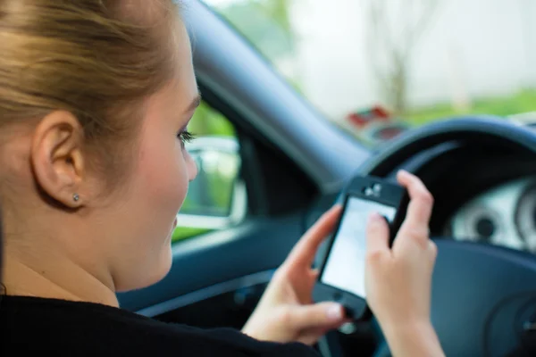 Молода жінка в машині з мобільним телефоном — стокове фото