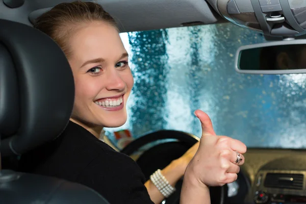 Jonge vrouw rijdt auto in wassen station — Stockfoto