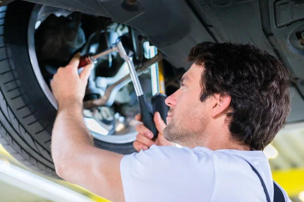 Mechanik praca w warsztacie samochód na koła — Zdjęcie stockowe