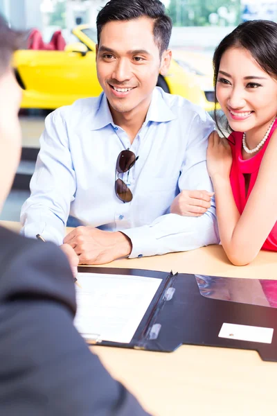 Couple signing sales contract for car at dealership — Stock Photo, Image