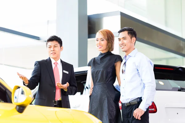 Pareja asiática comprando coche en concesionario — Foto de Stock