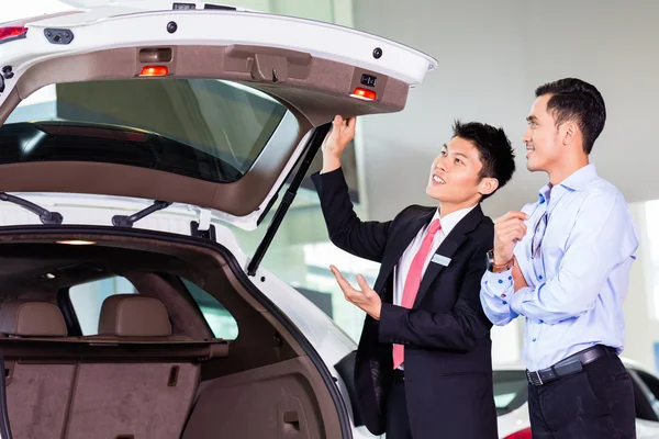 Asiático hombre mirando en coche en concesionario — Foto de Stock