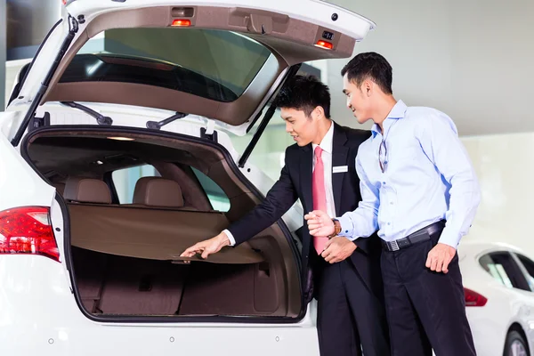 Azjatycki człowiek patrząc na samochód dealerskiej — Zdjęcie stockowe
