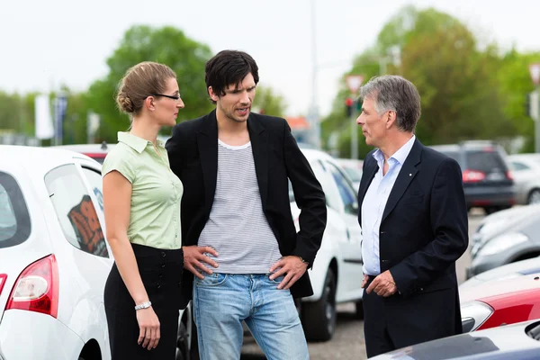 Pareja mirando el coche en el patio del distribuidor — Foto de Stock