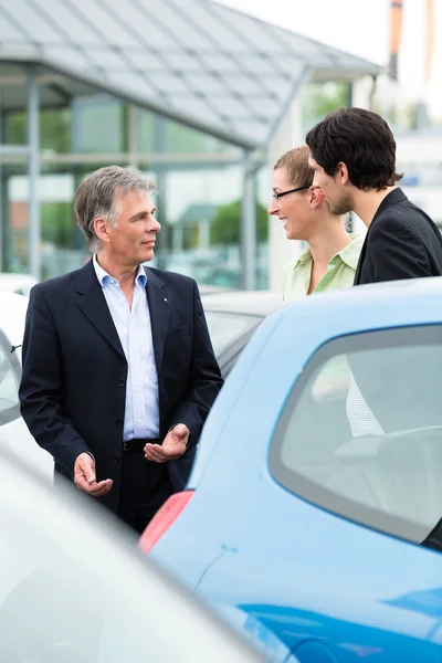 Couple looking at car on yard of dealer — Stock Photo, Image