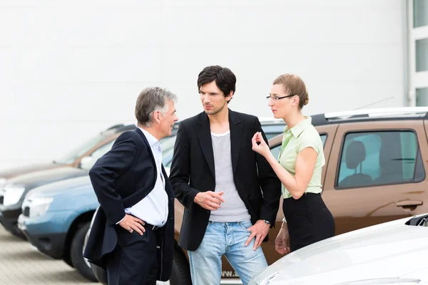 Pareja mirando el coche en el patio del distribuidor — Foto de Stock