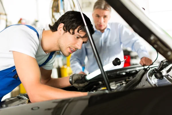 Homem e mecânico olhando para o motor do carro — Fotografia de Stock