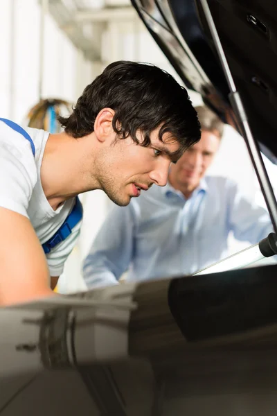 Hombre y coche mecánico mirando debajo de una capucha — Foto de Stock