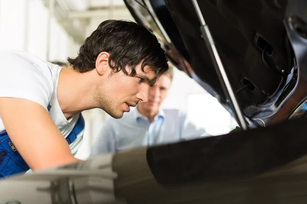 Uomo e meccanico auto guardando sotto un cofano — Foto Stock