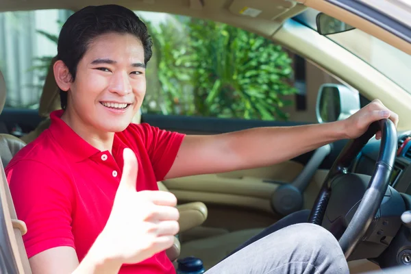 Азиатский мужчина за рулем новой машины — стоковое фото