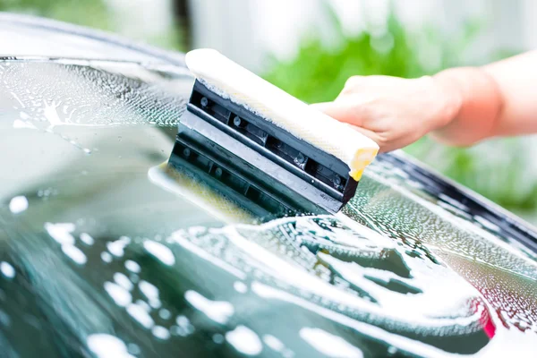 Hombre limpiando el parabrisas mientras el coche lava — Foto de Stock