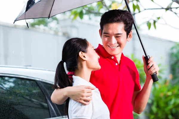 Пара, що йде з парасолькою через дощ — стокове фото