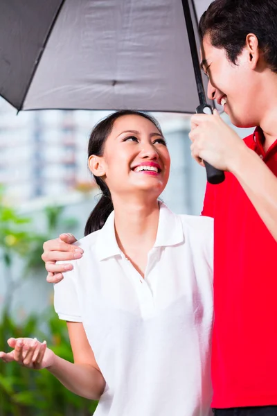 Casal andando com guarda-chuva através da chuva — Fotografia de Stock