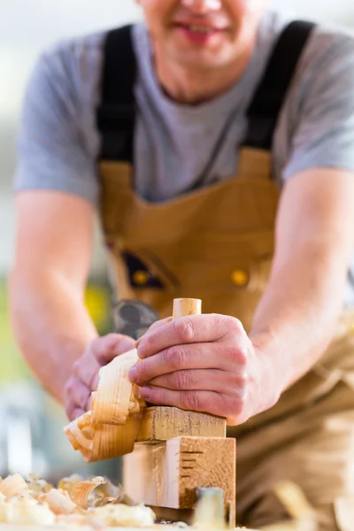 Timmerman met hout planer en werkstuk in timmerwerk — Stockfoto