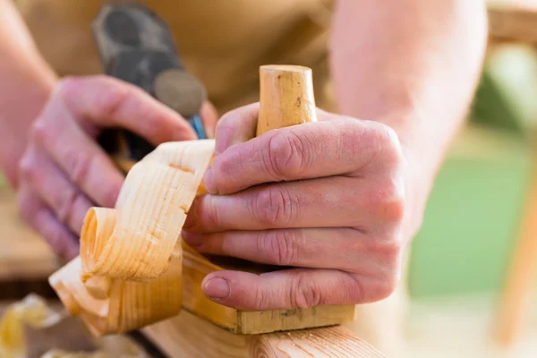 Carpintero con cepilladora de madera y pieza de carpintería — Foto de Stock