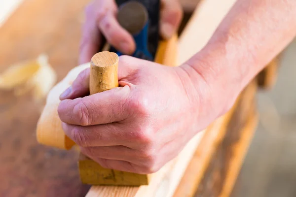 Carpintero con cepilladora de madera y pieza de carpintería — Foto de Stock