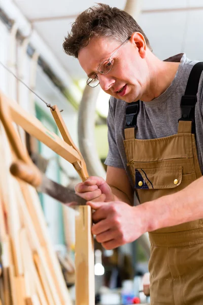 Carpinteiro usando serra manual — Fotografia de Stock