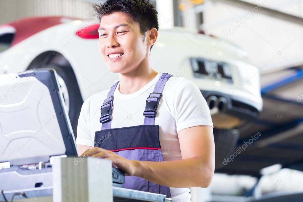Car mechanic with diagnosis tool in auto workshop