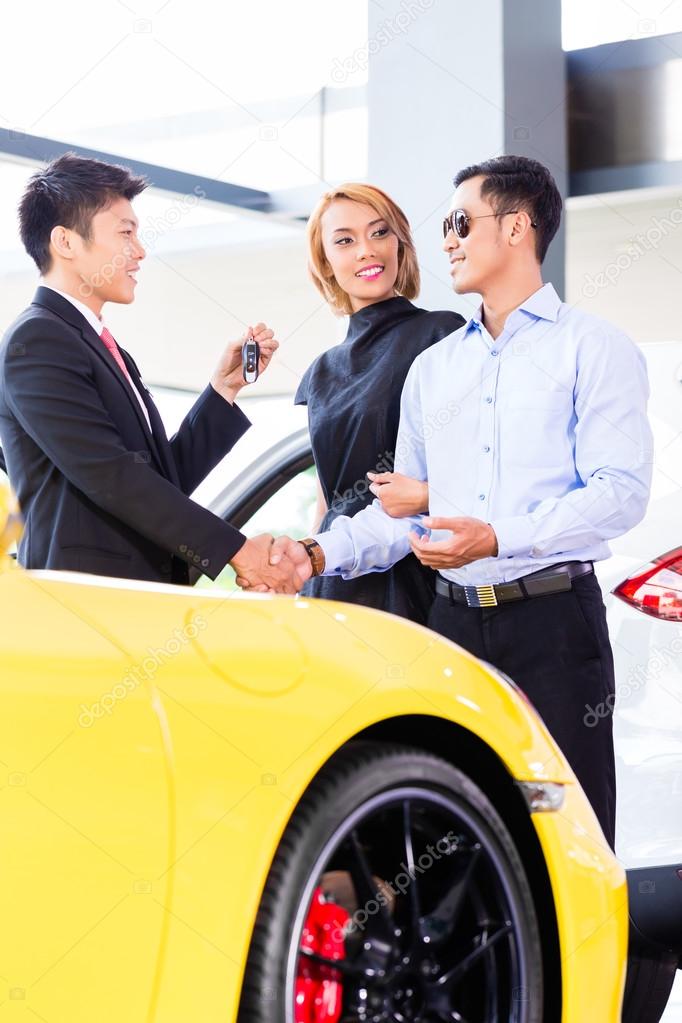 Asian couple buying car in dealership