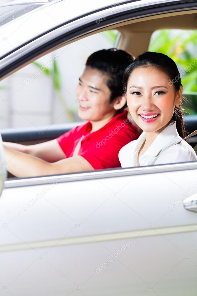 Asian couple driving new car