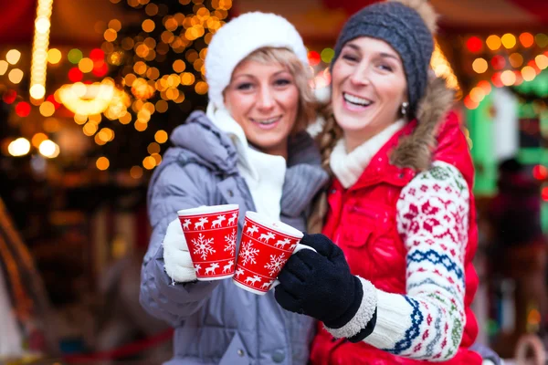 Vrienden gekruide wijn drinken op kerstmarkt — Stockfoto