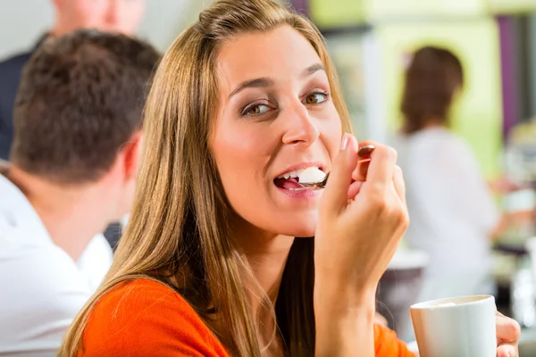 Młoda kobieta jedzenie krem w kawiarni — Zdjęcie stockowe