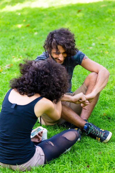 Latinska Hipster par sitter på ängen — Stockfoto