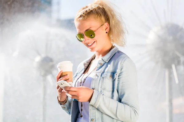 Жінка біля фонтану з телефоном і кавою — стокове фото
