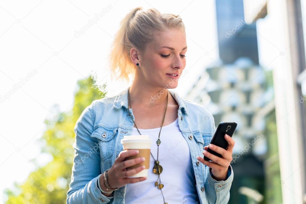 Woman with coffee and phone in city