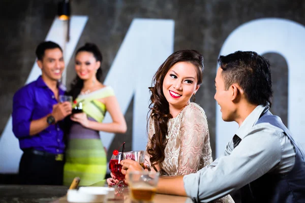 Couples flirting and drinking at nightclub bar — Stock Photo, Image