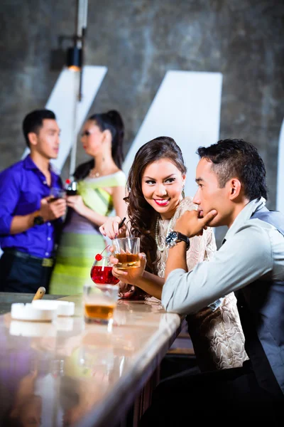 Parejas coqueteando y bebiendo en el bar de la discoteca —  Fotos de Stock