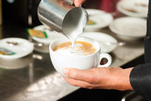 Barista maken cappuccino in zijn coffeeshop — Stockfoto