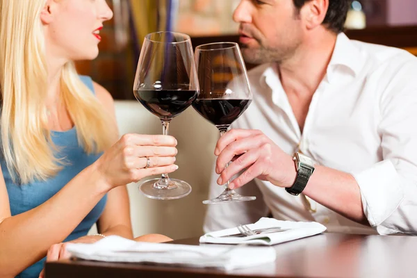 Pareja bebiendo vino tinto en restaurante Imagen de archivo