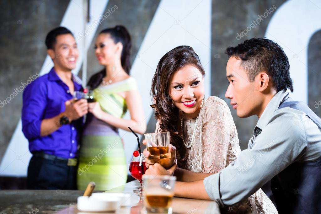 couples flirting and drinking at nightclub bar