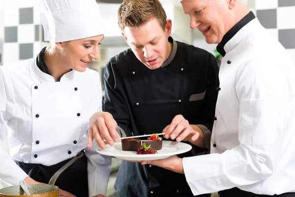 Kocken team i restaurangkök med dessert — Stockfoto