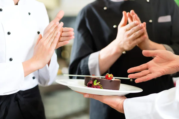 Equipo de chef en la cocina del restaurante con postre — Foto de Stock