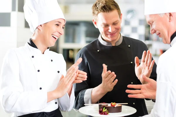 Equipo de chef en la cocina del restaurante con postre — Foto de Stock