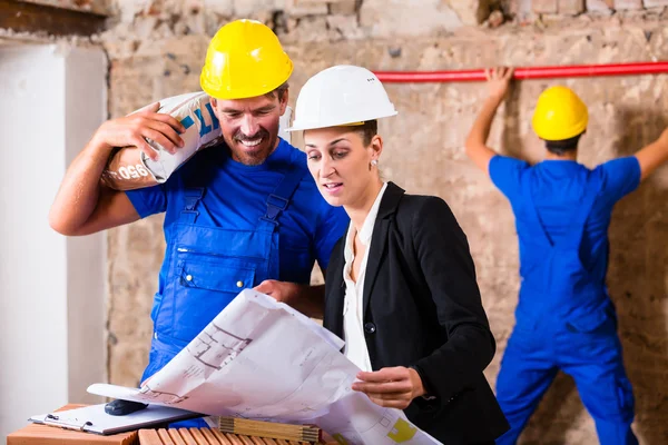 Arquitecto y trabajador de la construcción en obra con plan — Foto de Stock