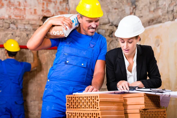 Arquitecto y trabajador de la construcción en obra con plan —  Fotos de Stock