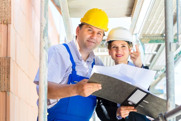 Construction Team with building plans on site — Φωτογραφία Αρχείου